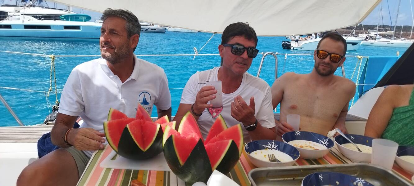 Socios del club de vela compartiendo comida fondeados en Baleares